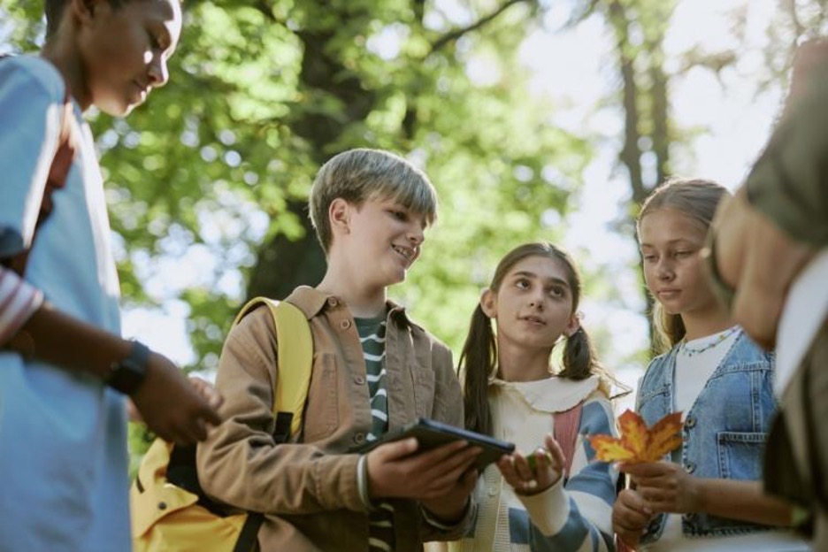 students smile while discussing their notes on an outdoor field trip
