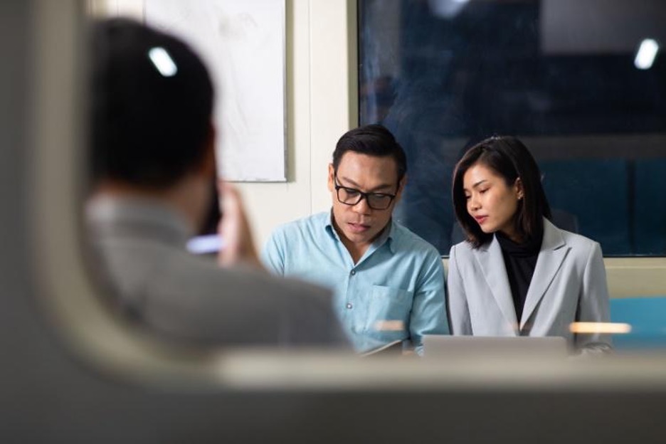 employees sit together and look at their laptop screens