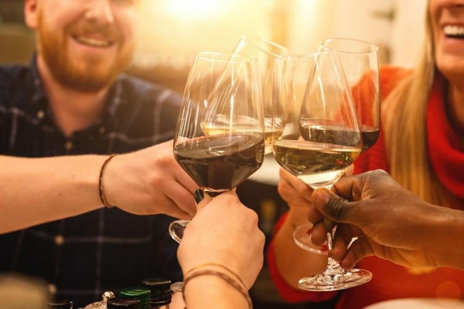 friends toast their wine glasses as the sun sets at a winery