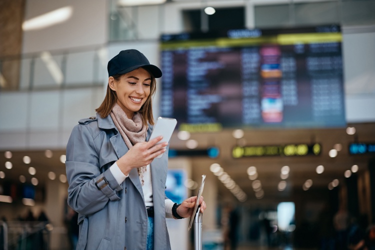 a woman looks at her phone in the entrance of an airport