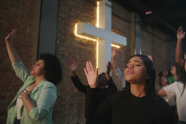 A group of worshippers pray in front of a Christian cross symbol