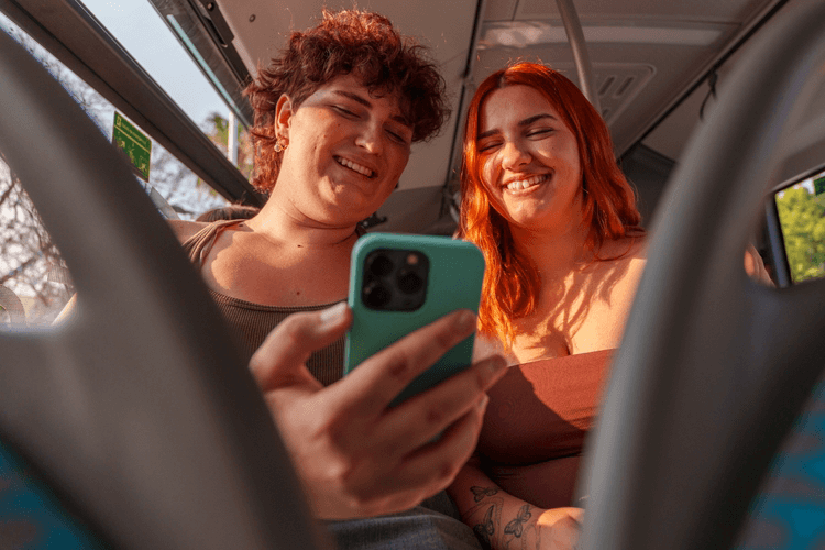 friends looking at a phone on a bus