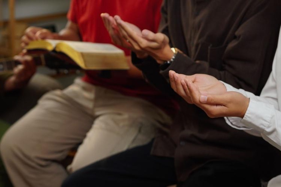 people gather and hold books and raise their hands
