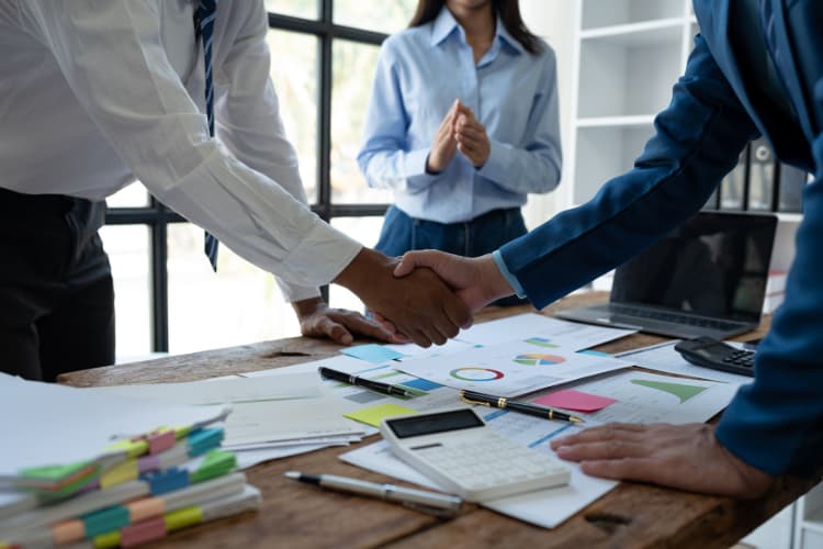 two coworkers shake hands in an office