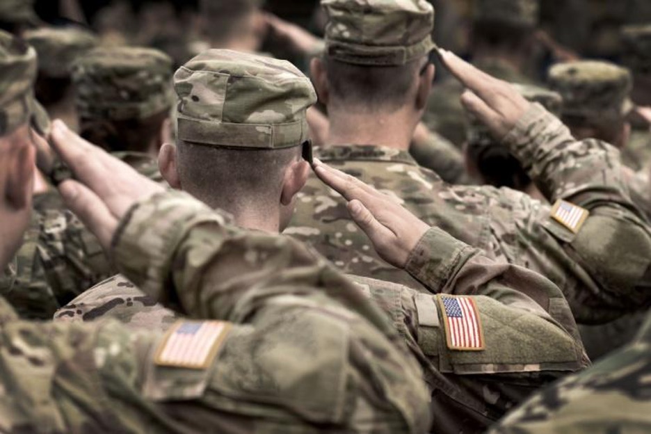soldiers in camo salute while standing in formation