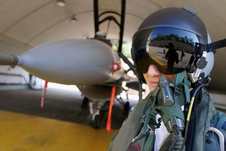 an air force pilot posing in front of his jet