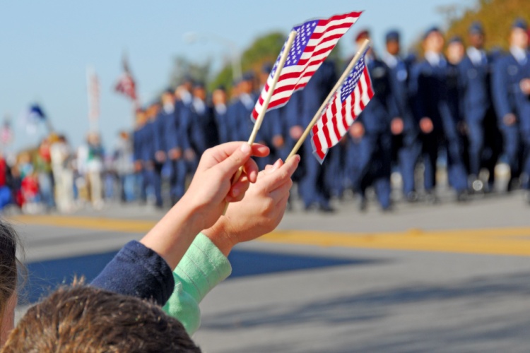 two children wave american flags at a veterans day parade