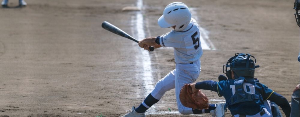 a youth baseball player swings a bat at a pitch