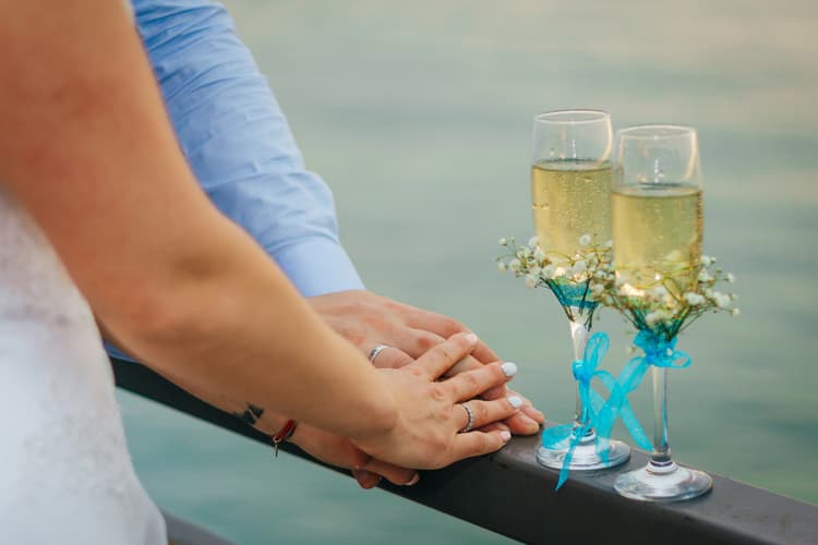 A couple holding hands besides two glasses of champagne