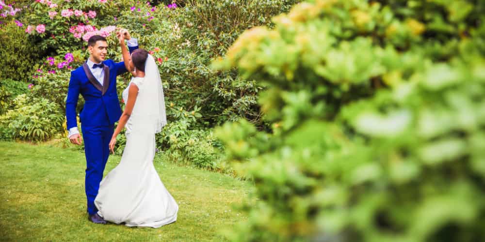 A happy wedding couple dances in a flower garden