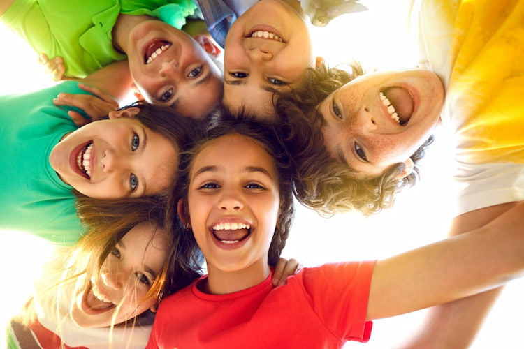 kids look down at the camera and smile on a sunny day