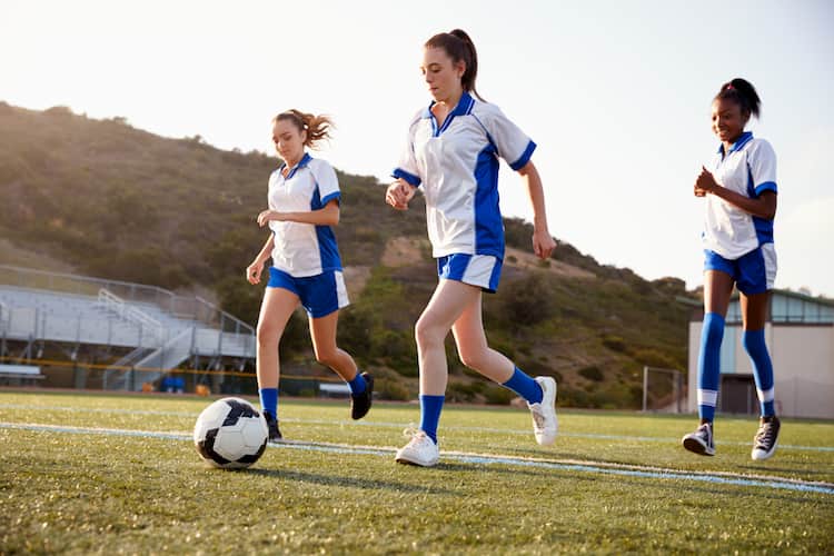 Three young women playing soccer